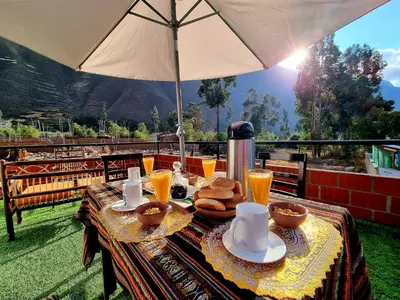 a table with food and drinks and an umbrella at Valle verde, Hostel & camping in Urubamba