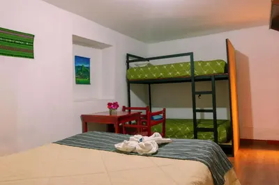 a bedroom with a bed and a desk and bunk beds at Valle verde, Hostel & camping in Urubamba