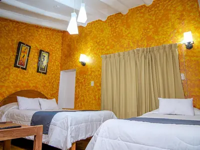 two beds in a room with yellow walls at LO NUESTRO House in Cusco