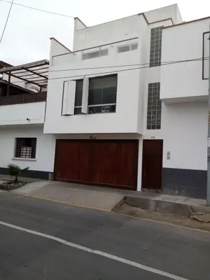 a white house with brown doors on a street at El Refugio in Punta Hermosa