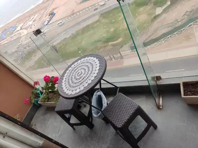 a table and chair on a balcony with a window at Arena Costa Lima private rooms Peru in Lima