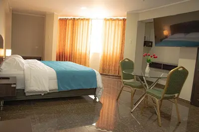 a bedroom with a bed and a table and chairs at Real Hotel in Huánuco