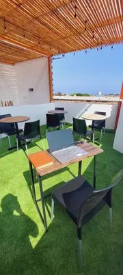 a table with a laptop on it in a room with chairs at Mandala in Pisco