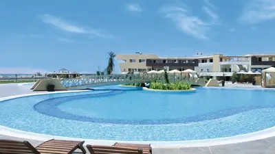 a large swimming pool with chairs and a bridge at Aranwa Paracas Resort & Spa in Paracas