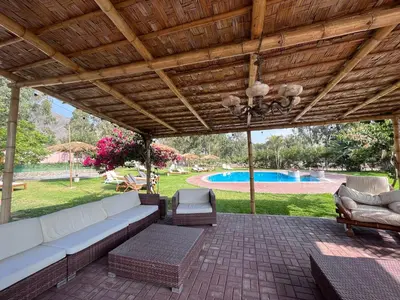 a covered patio with a couch and chairs and a pool at Bungalows de Casa Verde in Mala