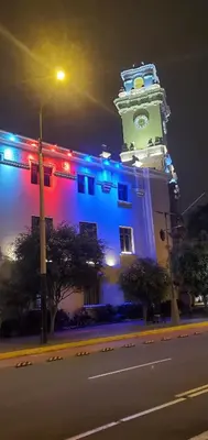 a building with a lit up clock tower at night at Waldorf in Lima