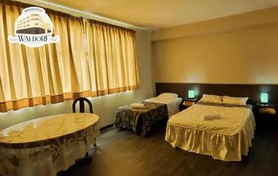 a hotel room with two beds and two tables at Waldorf in Lima
