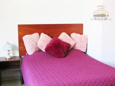 a bed with pink and purple pillows on it at Residencial Waldorf in Lima