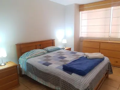 a bedroom with a bed with a blue blanket and a window at suite pardo CAA Miraflores in Lima