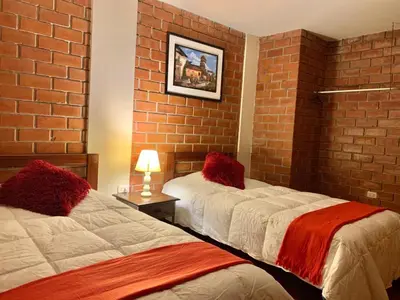 a bedroom with two beds and a brick wall at Hotel Colibri in San Vicente de Cañete