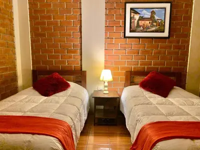 a bedroom with two beds and a brick wall at Hotel Colibri in San Vicente de Cañete