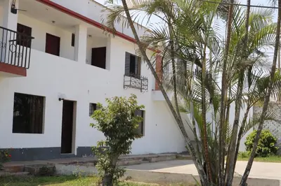 a white building with a palm tree in front of it at Los Naturales in Huaral