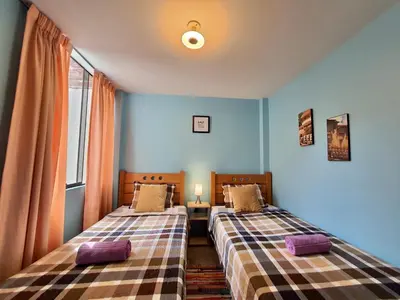 two beds in a room with blue walls at EL TUMI - Aeropuerto in Lima
