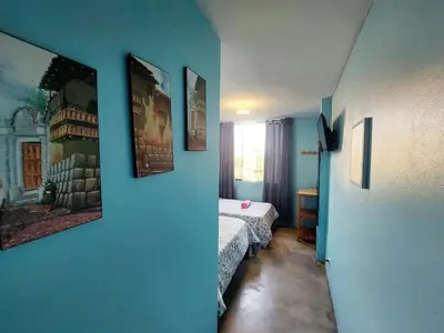 a blue room with a bed and pictures on the wall at EL TUMI - Aeropuerto in Lima