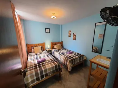 two beds in a room with blue walls at EL TUMI - Aeropuerto in Lima