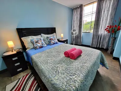 a bedroom with a bed with a red pillow on it at EL TUMI - Aeropuerto in Lima