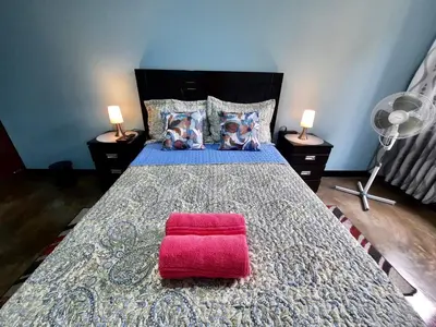 a bedroom with a large bed with a red pillow at EL TUMI - Aeropuerto in Lima