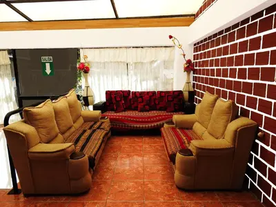 a living room with two chairs and a brick wall at Hostal Encanto Machupicchu in Machu Picchu