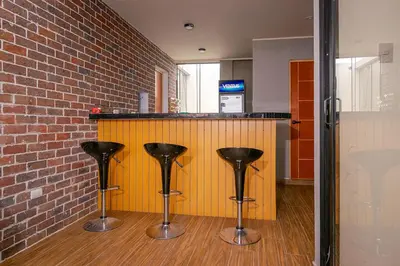 a bar with two black stools next to a brick wall at Hospedaje Muñoz in Ica