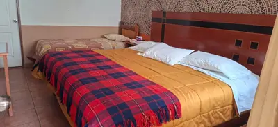 a bedroom with a bed with a plaid blanket at Hotel Manantial in Churín