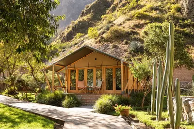 a small house with a mountain in the background at Las Qolqas EcoResort Ollantaytambo in Ollantaytambo