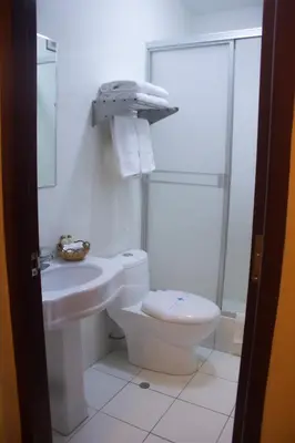 a white bathroom with a toilet and a sink at Royal Garden Hotel in Lima