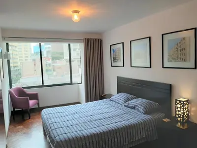 a bedroom with a bed and a chair and a window at Miraflores Kennedy's Park Apartment in Lima