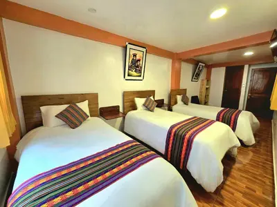 a hotel room with three beds in a room at Amakonkay Machupicchu in Machu Picchu