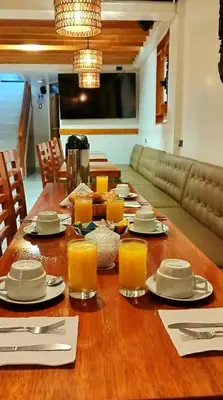 a wooden table with plates and glasses of orange juice at Amakonkay Machupicchu in Machu Picchu