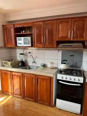 a kitchen with wooden cabinets and a stove top oven at Departamento Don Santiago Centro in Cusco