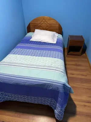 a bed in a room with a blue wall at Departamento Don Santiago Centro in Cusco