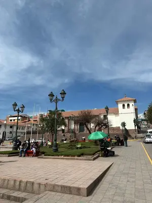 a group of people sitting in a park with a green umbrella at Departamento Don Santiago Centro in Cusco