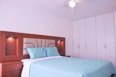 a bedroom with a bed with a wooden headboard and white cabinets at KYRA APARTMENTS - Central Miraflores - Spacious 4BR for 07 guests in Lima