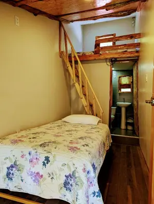 a bedroom with a bed with a staircase and a sink at FRANKFURTER HOF FAMILIAR Oxapampa in Oxapampa
