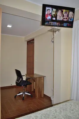 a desk and a chair in a room with a tv at Apartamentos Las Americas in Lima