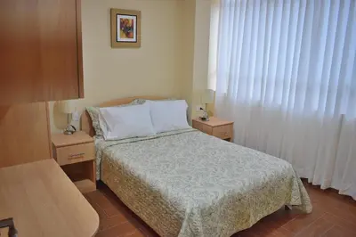 a small bedroom with a bed and two night stands at Apartamentos Las Americas in Lima