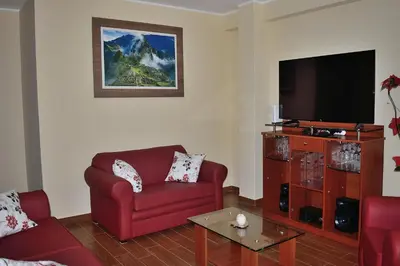 a living room with a red couch and a flat screen tv at Apartamentos Las Americas in Lima