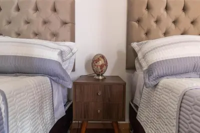 a bedroom with two beds and a nightstand with a lamp at Nakua Paracas Lodge in Paracas