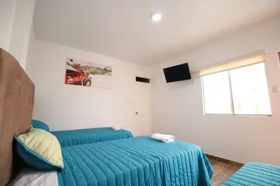 a bedroom with two blue beds and a window at Nakua Paracas Lodge in Paracas