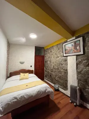 a bedroom with a bed and a stone wall at Hotel Choquequirao in Cusco