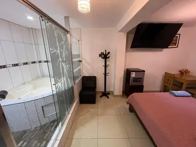 a bedroom with a tub and a bed and a television at Hostal Milagros in Chancay