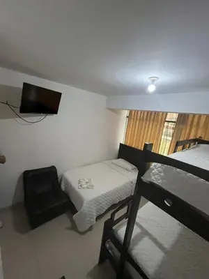 a small room with a bed and a chair and a television at Hostal Milagros in Chancay