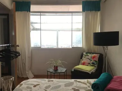 a bedroom with a bed and a chair and a window at Sunny Apartment in Cusco