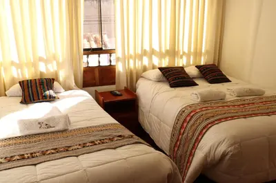 a bedroom with two beds and a window with curtains at Casa del Escultor in Cusco