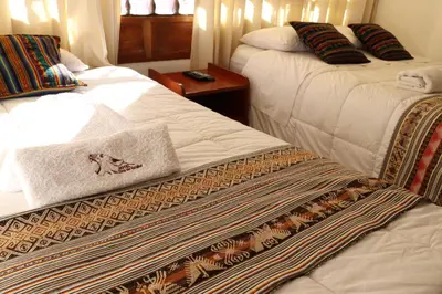 a hotel room with two beds and a table at Casa del Escultor in Cusco