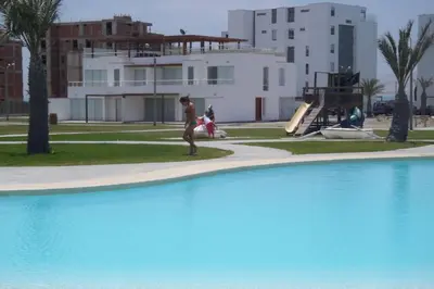 a man walking next to a blue swimming pool at PARACAS megaview bayfront flat in Paracas