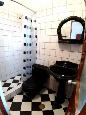 a bathroom with a black toilet and a mirror at HOSPEDAJE CENTRAL in Ayacucho