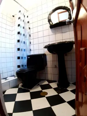 a bathroom with a black toilet and a sink at HOSPEDAJE CENTRAL in Ayacucho