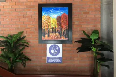 a painting hanging on a brick wall with a sign at 6 - Departamento de 2 dormitorios en area turistica de Miraflores in Lima