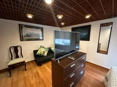 a living room with a large television and a chair at 2- Amplio Departamento remodelado en Miraflores in Lima
